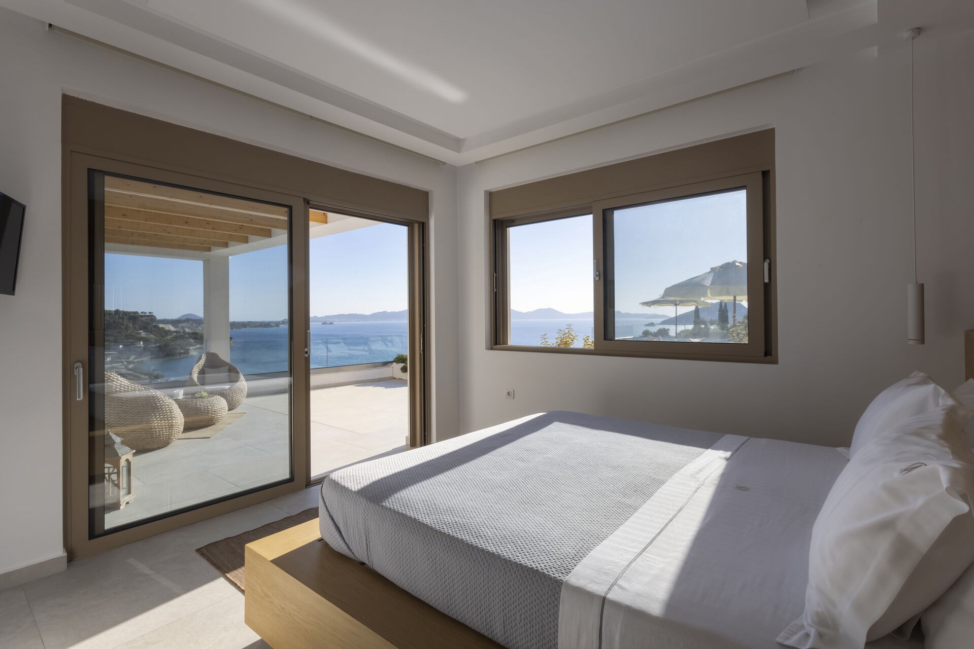 One of the villa's five bedrooms, opening onto the shared terrace with views over Keri Bay.