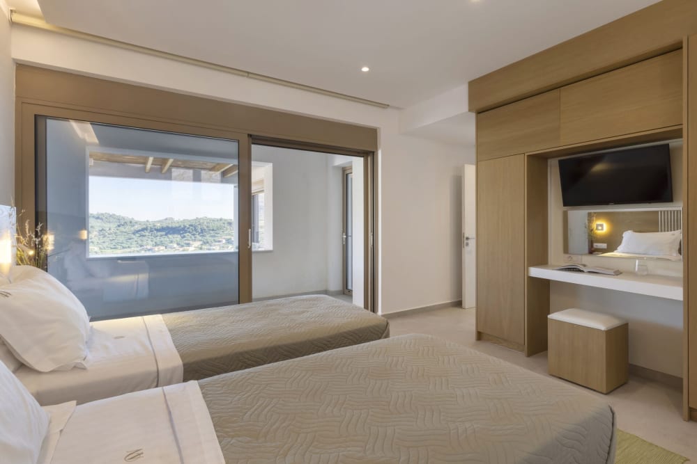 One of the villa's five bedrooms, opening onto the shared terrace with views over Keri Bay.